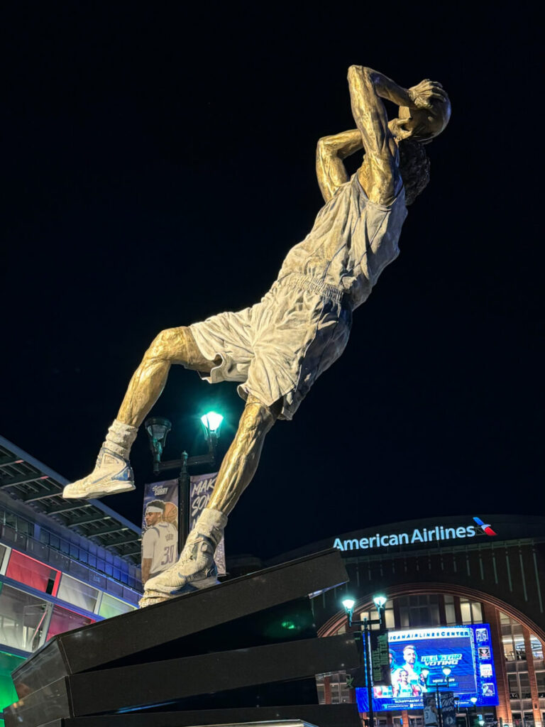 Dieses Bild zeigt die Dirk Nowitzki Statue vor dem Haupteingang des American Airlines Center Dallas