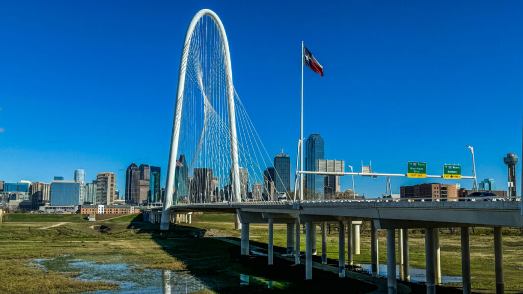 Dieses Bild zeigt die Margaret Hunt Hill Bridge und die Skyline von Dallas, Texas